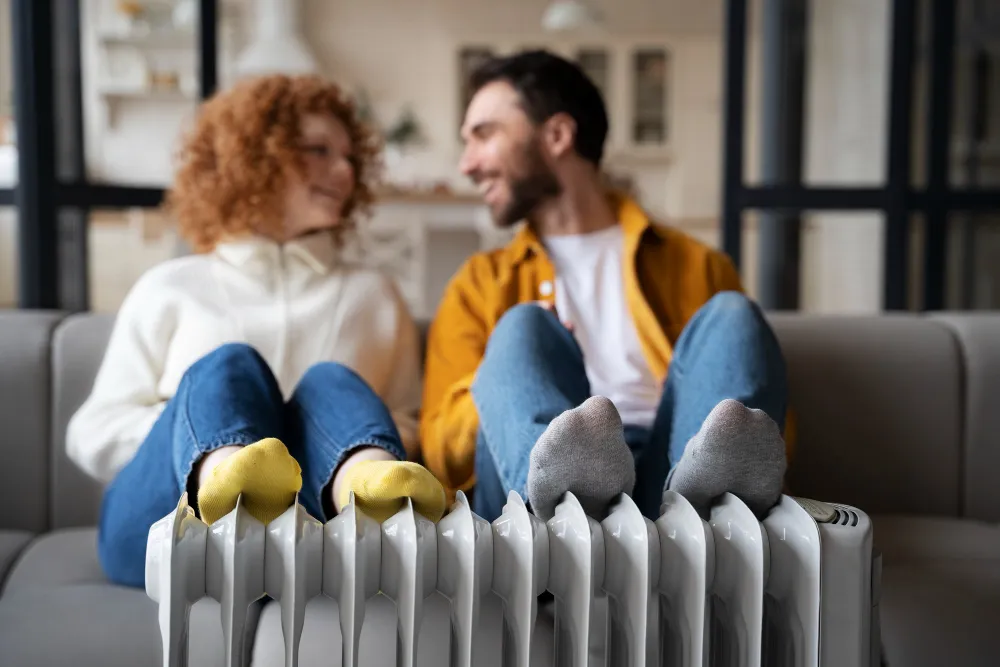 Un couple se réchauffe les pieds sur un radiateur.